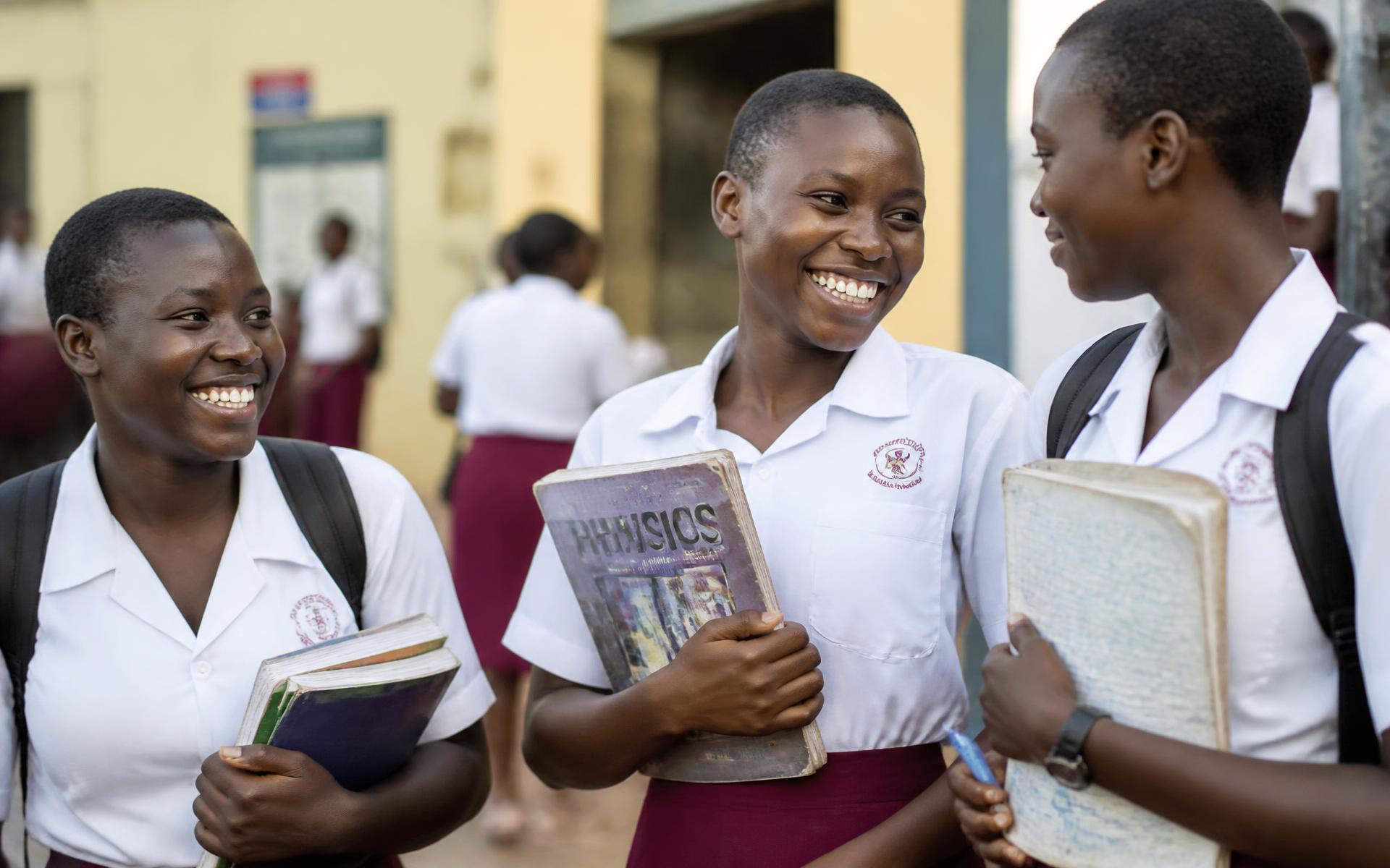 Ugandan schoolgirls smiling with schoolbooks